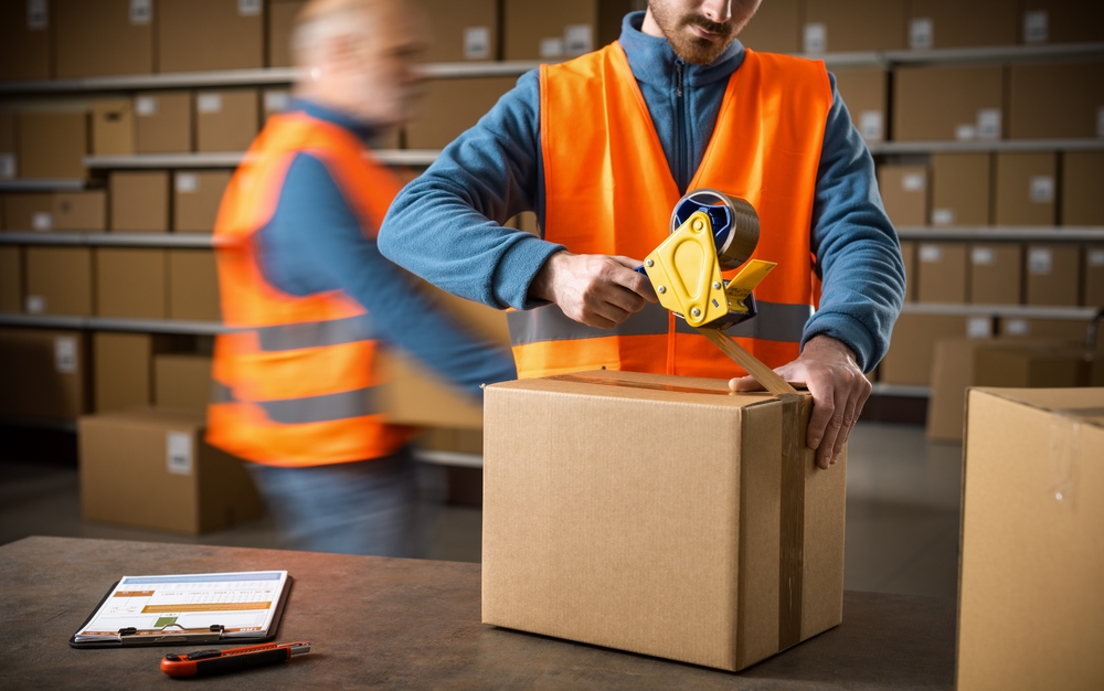 Warehouse workers packing boxes, representing labor supply and demand in logistics and supply chain operations.