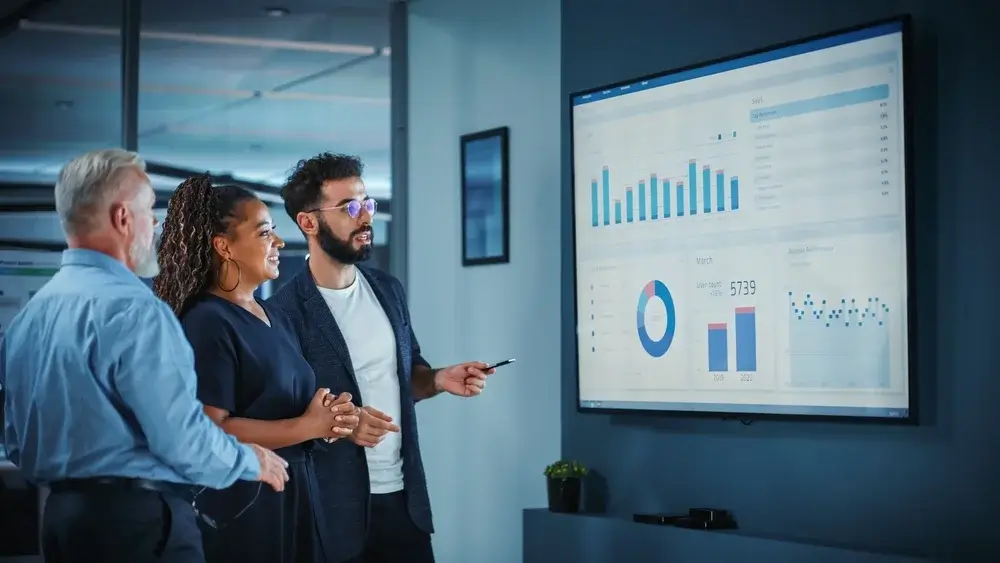 A diverse team reviewing market analysis data on a digital dashboard.