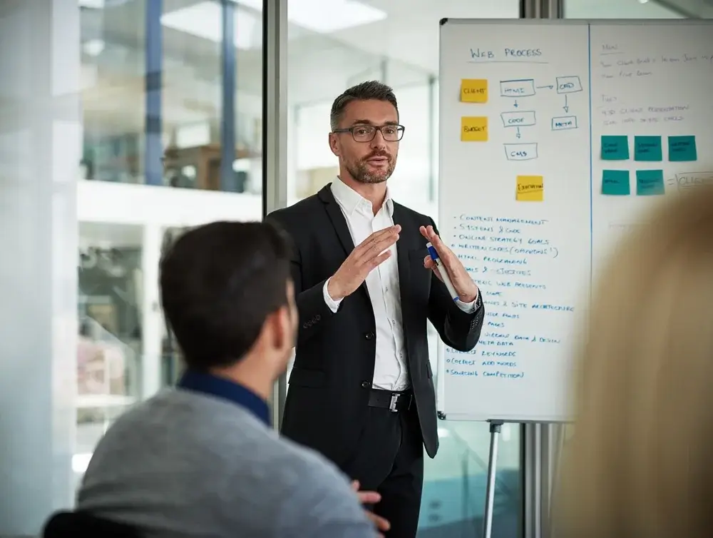 Business professional presenting strategy on a whiteboard, focusing on RFP response development for winning proposals.