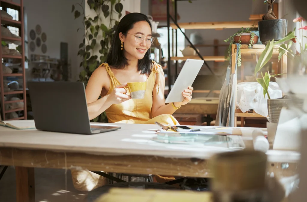 A small business owner working on a digital tablet in a creative workspace, exploring funding opportunities through Small Business Innovation Research Assistance.